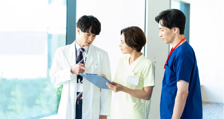 医療関係者が3人でカルテを見ながら話している様子